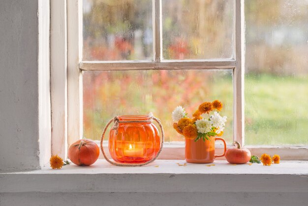 Autumn flowers and pumpkins  on old white windowsill