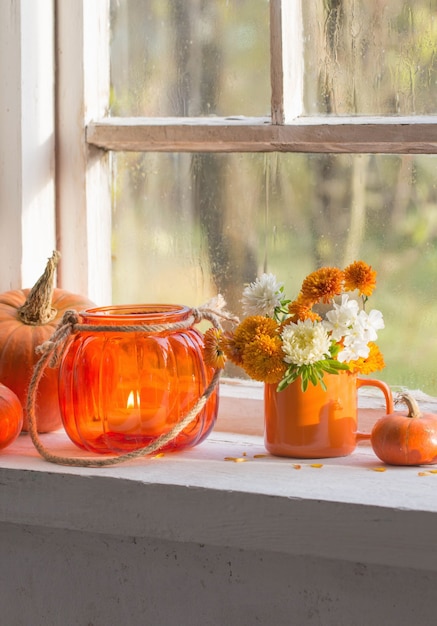 Autumn flowers and pumpkins  on old white windowsill