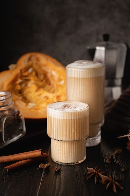 Photo autumn food and drink. seasinal drinks. pumpkin spicy latte with cream and spice, front view, dark background