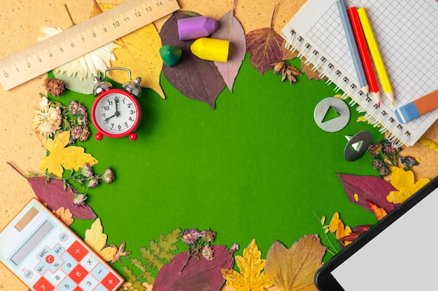 Autumn frame of dry leaves and school supplies. 