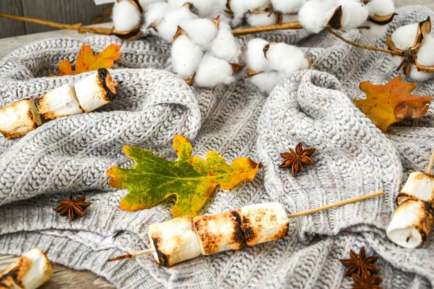 Autumn frame made of fall leaves, marshmallows, nuts, cinnamon, cotton sweater. Top view on wood background. Fall composition. Ornament For Thanksgiving