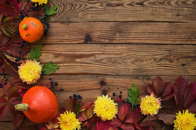 Autumn frame - red leaves, pumpkins, flowers on a dark wooden wood background top view. copy space for inscriptions, top view, space for text. Thanksgiving concept.