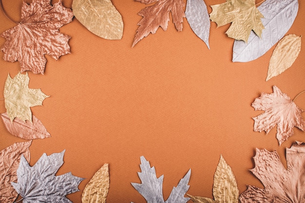 Blocco per grafici dorato dei fogli di autunno sull'arancio