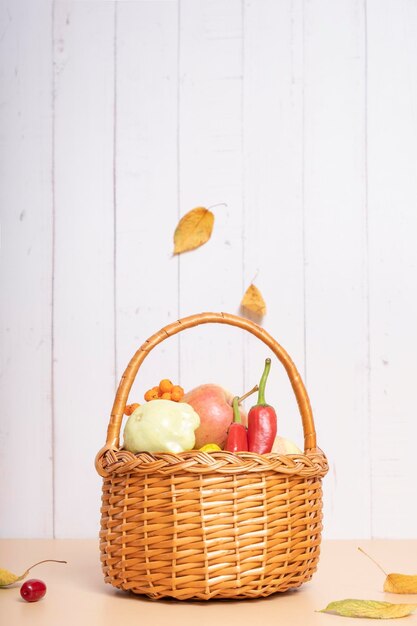 Autumn harvest basket with apples zucchini and peppers on a wooden background