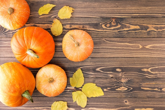 Autumn Harvest.  Pumpkins with autumn leaves on wooden background with copy space. Top view.