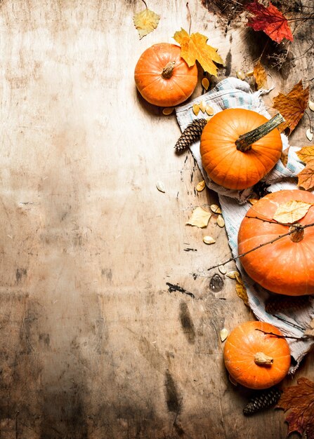 Raccolto autunnale zucca matura con foglie su fondo in legno