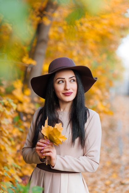 Foto autunno nelle sue mani giovane donna con un cappello a bordi larghi con le foglie come prova dell'autunno