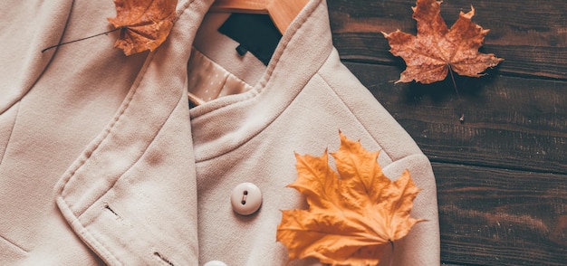 Autumn home cozy composition with a scarf and maple leaves on a wooden background