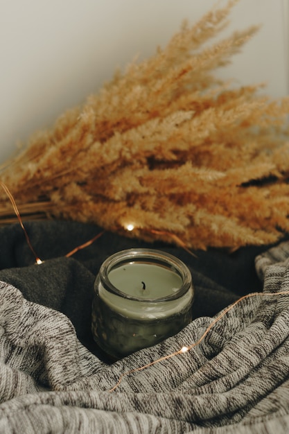 Autumn home decor with a candle and dry plant