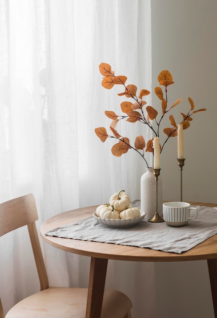 Photo autumn home interior in the living room around wooden table a chair a bouquet of autumn leaves in a vase decorative pumpkins cozy home