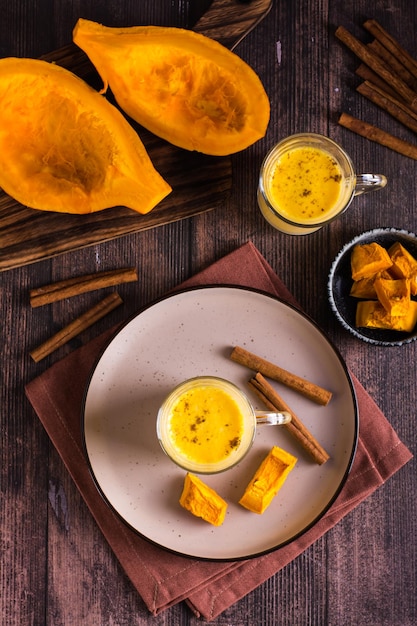 Autumn homemade pumpkin latte with cinnamon in glasses and pieces of pumpkin Top and vertical view