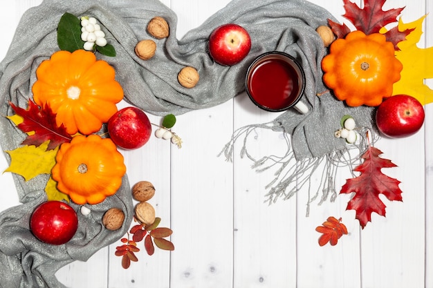 Autumn horizontal background with orange pumpkins and red apples nuts tea cup leaves and scarf