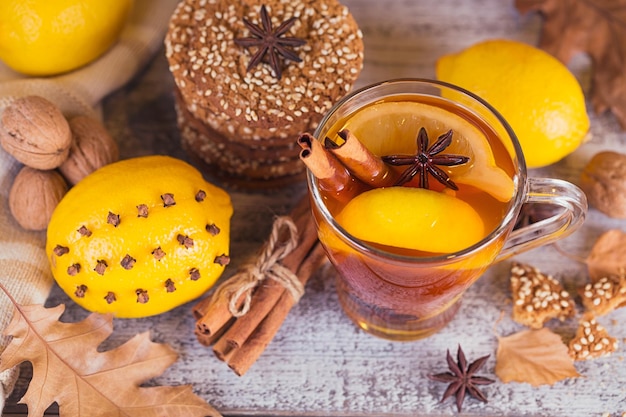 Autumn hot tea with lemon and spices in glass cup