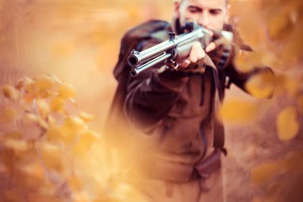 Autumn hunting season hunter aiming rifle in forest barrel of a gun