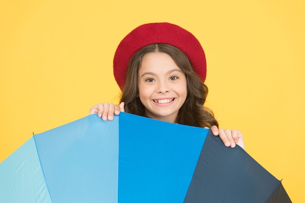 Autumn is in the air. Happy small kid with open umbrella on yellow background. Little child smile with umbrella. Rainy autumn weather. Fashion autumn accessory. Autumn season.