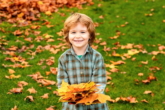 Осенний малыш мальчик в осеннем парке счастливый ребенок бросает опавшие листья, играя в ауту