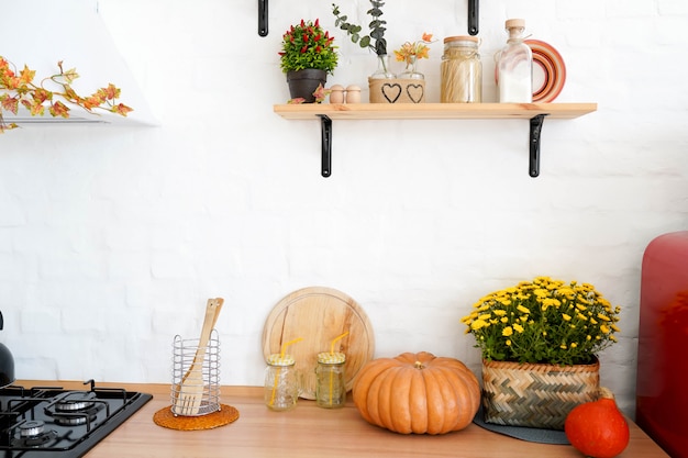 Autumn kitchen interior with shelfs, yellow flowers and pumpkin