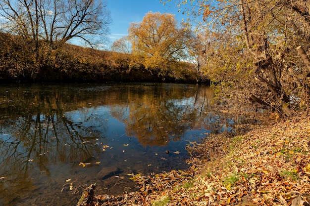 Autumn landscape on the river bank with sky reflection..