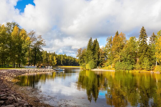 Autumn landscape trees on lake shore under blue sky with white clouds