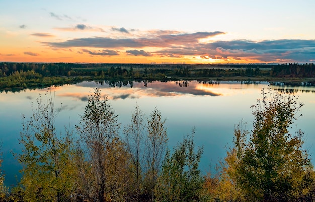 Autumn landscape with beautiful clouds over the lake at sunset. Leningrad region.