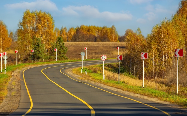 写真 黄色い白樺と真ん中に固い帯があるアスファルト高速道路のある秋の風景