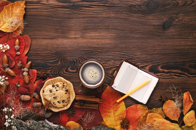 Foto foglie di autunno, biscotti e taccuino di carta su legno