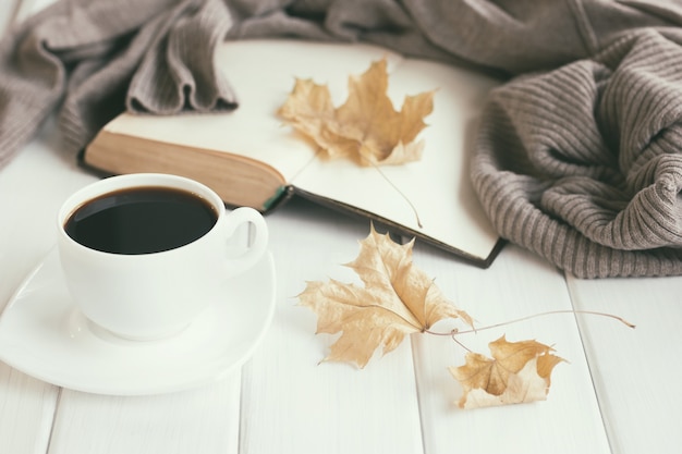 Фото Осенние листья чашка кофе теплый шерстяной свитер с открытой старой книгой
