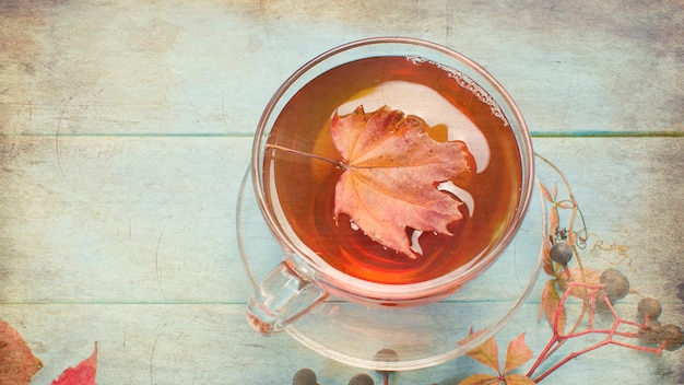 Autumn leaves and cup of tea on wooden table 