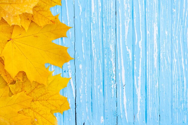 秋の葉のフレームを木製の背景の上から見ると秋の境界は黄色とオレンジ色の葉でヴィンテージの木材です