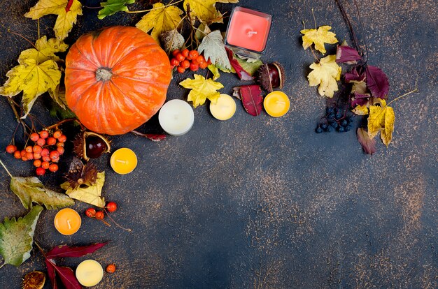 Foglie di autunno, zucca, castagne, candele su un buio