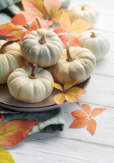 Autumn leaves and pumpkins over old wooden background