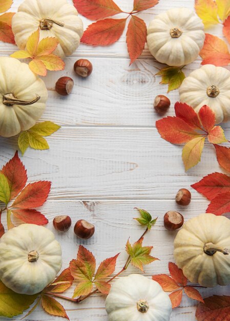 Autumn leaves and pumpkins over old wooden background