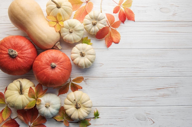 Autumn leaves and pumpkins over old wooden background