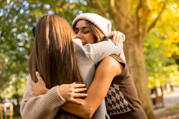 Photo autumn lifestyle women friends hugging in a park in autumn at sunset