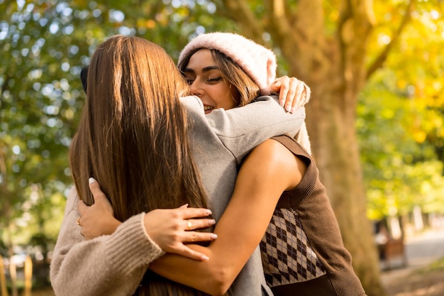 Autumn lifestyle women friends hugging in a park in autumn at sunset