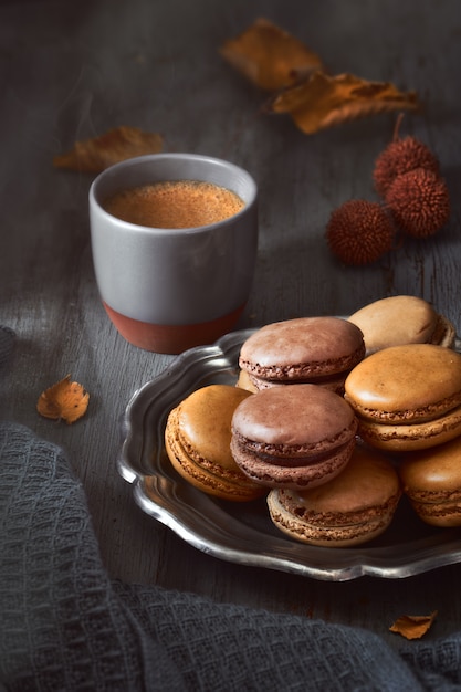 Autumn macarons with coffee on dark rustic wood