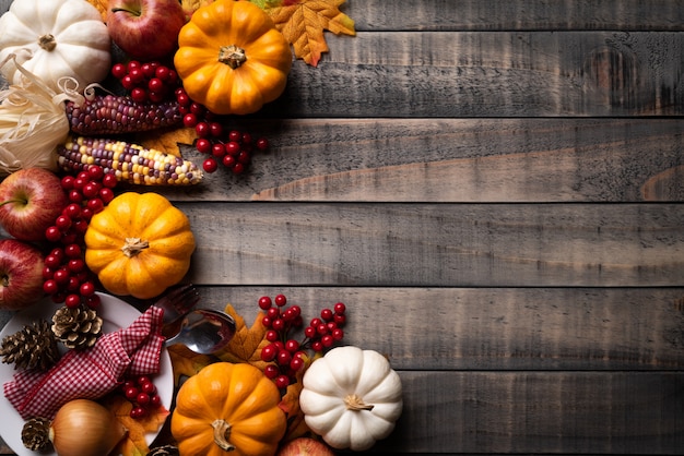 Photo autumn maple leaves with pumpkin, corn and red berries