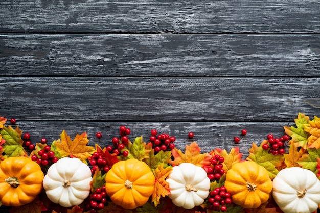 Autumn maple leaves with Pumpkin and red berries on old wooden background. 