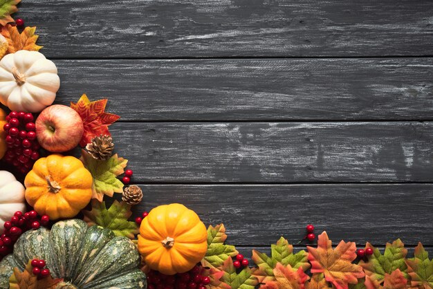 Autumn maple leaves with Pumpkin and red berries on old wooden.