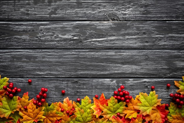 Autumn maple leaves with red berries on old wooden background. Thanksgiving day concept.