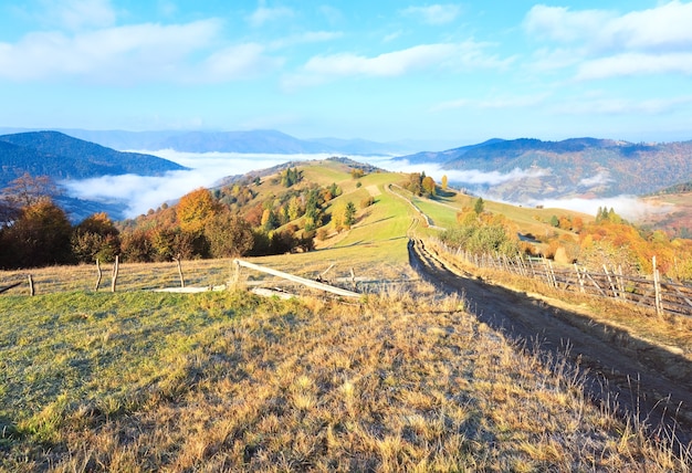 干し草の山と田舎の汚れた道のある秋の霧のかかった朝の高原（Mighgirya村の郊外、カルパティア山脈、ウクライナ）。