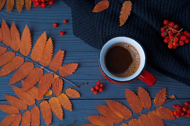 秋の気分秋の背景 一杯のコーヒー ニット スカーフ明るい葉と暗い木製のテーブルの果実