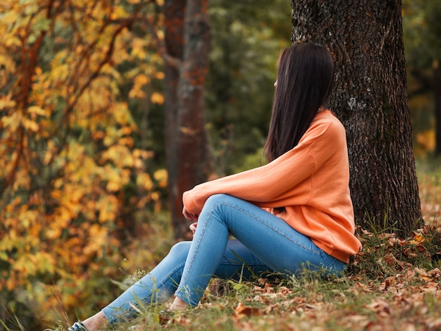 Autumn mood. Beautiful girl in orange hoodie in autumn Park