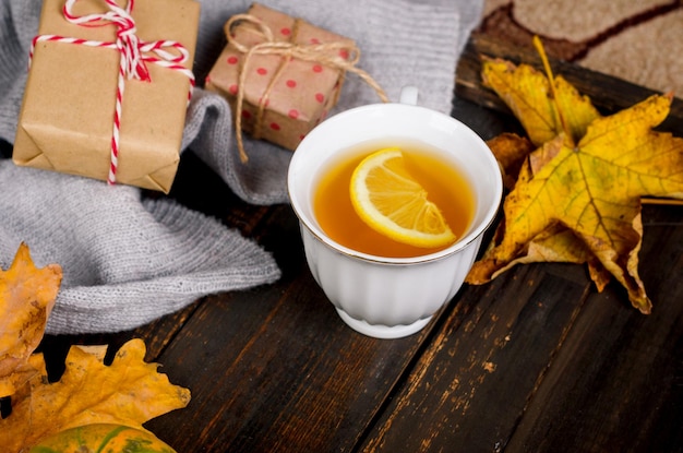 Autumn mood concept Hot tea with lemon and leaves on wooden background