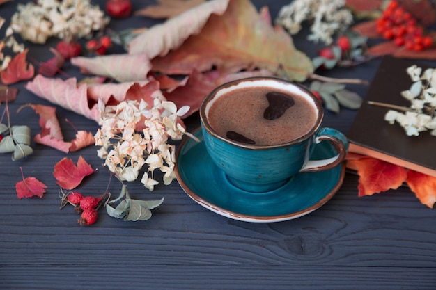 Autumn mood a cup of coffee among autumn leaves on a wooden dark table Texture of leaves and berries