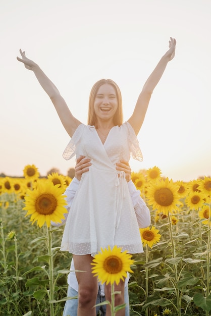 가 자연입니다. 일몰에 해바라기 밭에서 걷는 젊은 로맨틱 커플