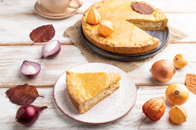 Autumn onion pie and cup of coffee on white wooden