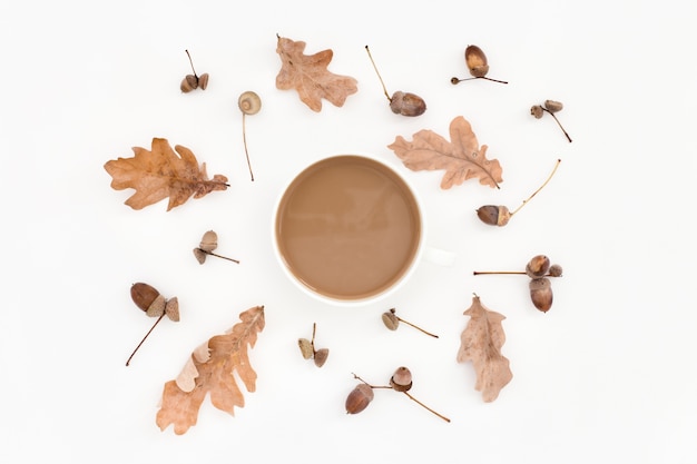 Autumn pale pattern, leaves, acorns and cup of coffee on white