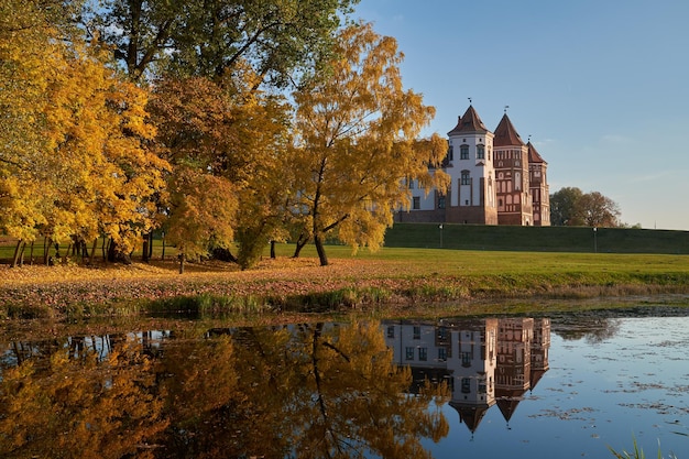 Parco autunnale con laghetto e antico castello medievale nella cittadina di mir, regione di grodno, bielorussia