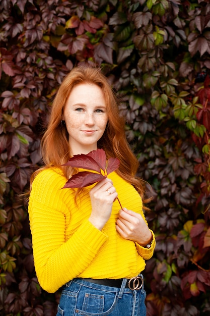 Autumn. portrait of a beautiful happy red-haired girl in a yellow jumper among the autumn leaves. color. atmosphere. a place for text. high quality photo